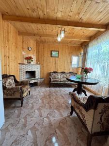 a living room with a table and a fireplace at Friendly Cottage with small Pool in Ambrolauri