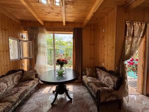 a living room with couches and a table and a window at Friendly Cottage with small Pool in Ambrolauri