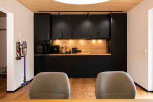 a kitchen with black cabinets and two gray chairs at Hinterland&See in Tettnang