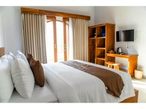 a bedroom with a large white bed with a window at Arthas Villa Nusa Penida in Polilit +27 photos