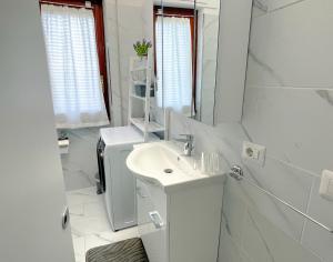 un bagno bianco con lavandino e specchio di SEA PEARL Boutique Apartment - Bright and spacious, with modern Mediterranean décor, just 100 meters from the Lavinio seafront ad Anzio Altre 22 foto