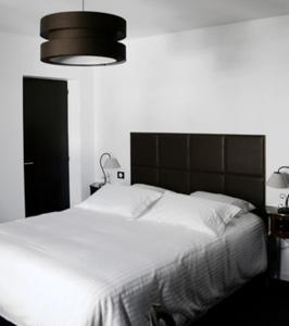 a bedroom with a large white bed with a black headboard at L auberge de la pointe in Soustons