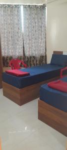 a bedroom with two beds and a red chair at Bhagini Residency Rooms in Bangalore