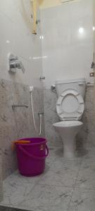 a bathroom with a toilet and a purple bucket at Bhagini Residency Rooms in Bangalore
