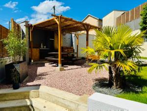 a patio with a wooden pergola and palm trees at Le Clos Les Brunes in Limoges