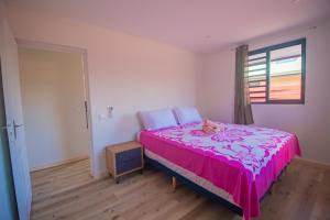 a bedroom with a pink bed with a stuffed animal on it at Bora Bora House Maha in Bora Bora
