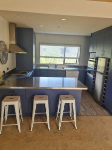 a kitchen with a blue counter and two stools at Harrisons Retreat Premium Stay in Cable Bay
