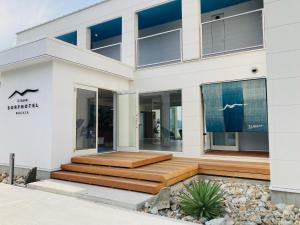 a white house with a wooden deck in front of it at WakasaSurfHotel ILMARE in Takahama