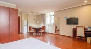 un salon avec une table, des chaises et une télévision dans l'établissement GreenTree Inn Wuxi Changjiang North Road Jincheng Road Express Hotel, à Fangqian