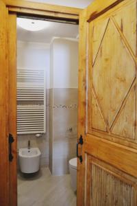 a bathroom with a wooden door and a toilet and a sink at Maison Carrel Elegant 7 in Breuil-Cervinia