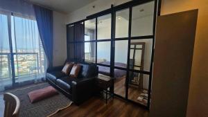 a living room with a leather couch and a large window at Condo Sea view Beach U 34 in Pattaya South