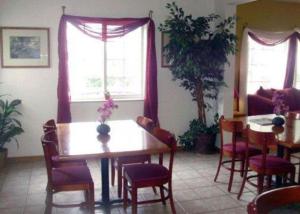 a dining room with a table and chairs and two windows at Rodeway Inn Salina North in Salina