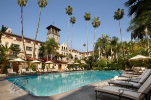 Una piscina en un hotel con sillas y palmeras. en The Mission Inn Hotel and Spa, en Riverside