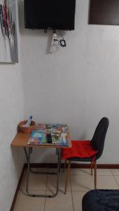 a table with a chair and a television on a wall at Habitación privada in Iquique