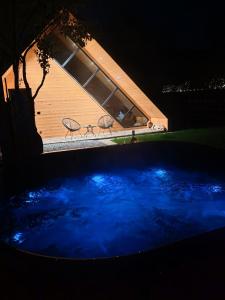 basen z niebieską wodą przed domem w nocy w obiekcie La Livada Chalet w mieście Vişeu de Sus