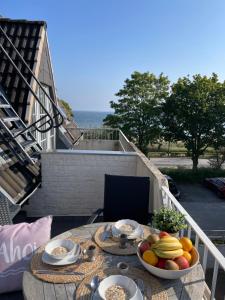 a table with a bowl of fruit on a balcony at Strandliebe - Beach Apartment mit Meerblick in Harrislee