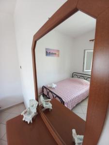 a mirror reflecting a bedroom with a bed in a room at Thalia`s Apartment near the beach in Nea Kalikratia