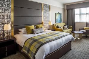 una habitación de hotel con una cama grande y sillas en ABode Glasgow, en Glasgow