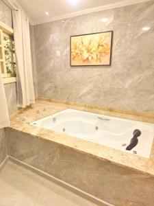 een badkuip in een badkamer met een schilderij aan de muur bij Pousada Beira Rio in Santo Antônio do Pinhal +50 foto's