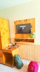 a room with a desk and a television and luggage at Chand Guest house in Kasol