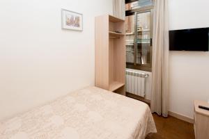 a small bedroom with a bed and a television at Hostal Excellence in Barcelona