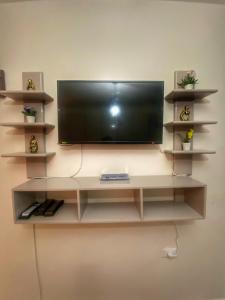 ein Flachbildfernseher an einer Wand mit Regalen in der Unterkunft Studio Carmen with a Pool View in El-Alamein