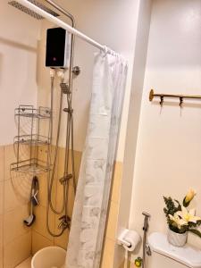 une salle de bain avec un rideau de douche et des toilettes dans l'établissement Condo in Greater Lagro Trees Residences 1, à Manille