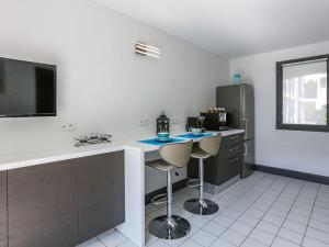 cocina con 2 taburetes y TV en Residence l 'agora, en Vaux-sur-Mer