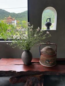 a vase with flowers on a table with a window at Ananda Home in Tân Hiệp +38 photos