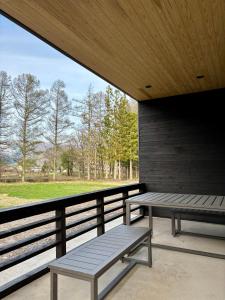 a porch with two benches and a view of a park at Kinagashi Happo Chalet West in Hakuba