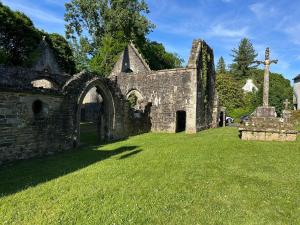 an old stone church with a cross in the grass at Appartement, terrasse de plain-pied in Plounéventer
