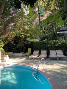 a swimming pool with two chairs and a table at Le Windsor, Jungle Art Hotel in Nice