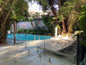 a swimming pool with a table in front of a fence at Le Windsor, Jungle Art Hotel in Nice