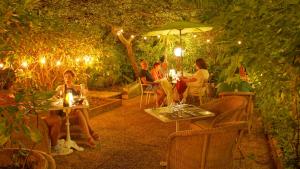a group of people sitting at tables in a garden at night at Le Windsor, Jungle Art Hotel in Nice
