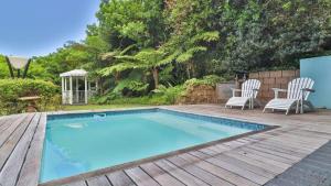 a swimming pool on a wooden deck with two chairs at Blue Home Sedgefield in Sedgefield