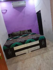 マトゥラーにあるJay Shree Radhey Home Stay Near 300mtr From Mathura Junction Railway Stationの紫の壁のドミトリールームのベッド1台分です。