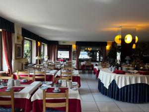 a restaurant with tables with red and white table settings at Hotel Edelweiss & SPA in Cesana Torinese