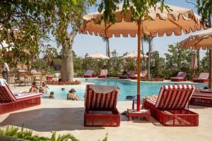 a pool with chairs and umbrellas and people swimming at The Red - a GiGi Residence in Mājid Abū Zayd