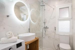 a white bathroom with a sink and a shower at Dioni, Central Luxury Apartment in Samos +19 photos