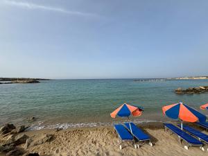 a group of chairs and umbrellas on a beach at Villa Eden Palms, Coral-Bay, Pool in Peyia