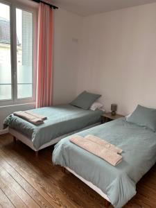 two beds in a room with a window at Maison proche Disneyland paris in Boissy-Saint-Léger