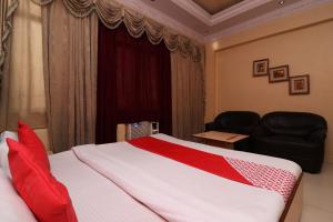 丹巴德Super Hotel O Akash Regency的一间卧室配有一张带红色枕头的床和一张沙发