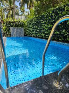 a swimming pool with blue tile around it at Nexus Green Resort in Calangute