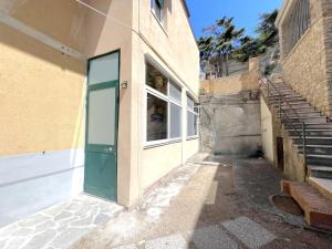 une ruelle vide avec une porte verte et des escaliers dans l'établissement Marea, vicino mare con parcheggio by Alfareal, à Castiglione della Pescaia
