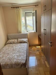a small bedroom with a bed and a window at Apartman Tafra 3 in Igalo