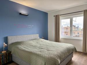 a bedroom with blue walls and a bed with a window at Japy 0401 - Modern 3-Bedroom Apartment in De Panne