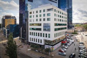 a tall white building with cars parked in a parking lot at 100 square meter 4-room central smart apt in Tallinn