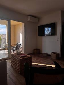 a living room with a television and a table and chairs at Appartement neuf, proche des plages et centre ville in Saint-Florent