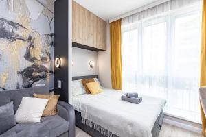 a bedroom with a bed and a couch and a window at miniSTUDIOS URSUS by VAYA STAYS in Warsaw