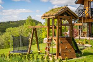 a playground with a wooden play structure in a yard at Bieszczadzka Hawira - Domki w Centrum przy Jeziorze z Widokiem dla Rodzin in Polańczyk